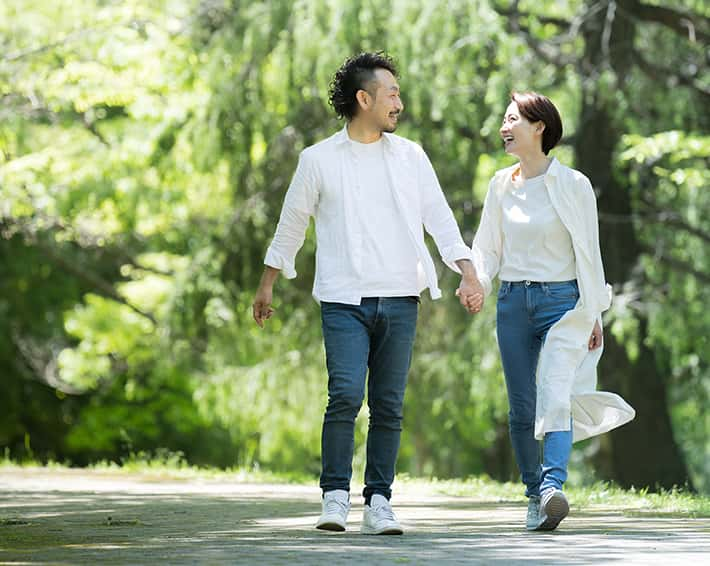 手を繋いで歩く男女の画像